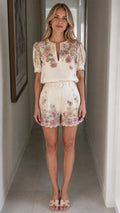 Front view of woman wearing off-white floral top and matching shorts set