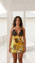 Front view of woman wearing yellow tie-dye mini slip dress with black lace trim