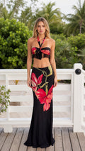 Front view of model wearing black floral halter crop top and maxi skirt set