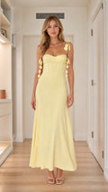 Front view of woman wearing yellow corset maxi dress with petal straps
