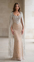 Front view of nude crystal embellished cape sleeve evening gown