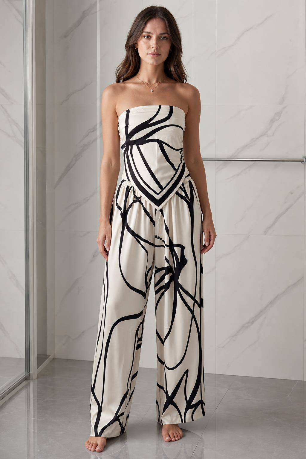 Front view of woman wearing beige and black abstract print strapless jumpsuit
