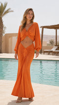 Front view of woman wearing vibrant orange twist-front cutout maxi dress by a pool