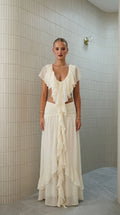 Front view of model wearing ivory ruffled two-piece maxi set