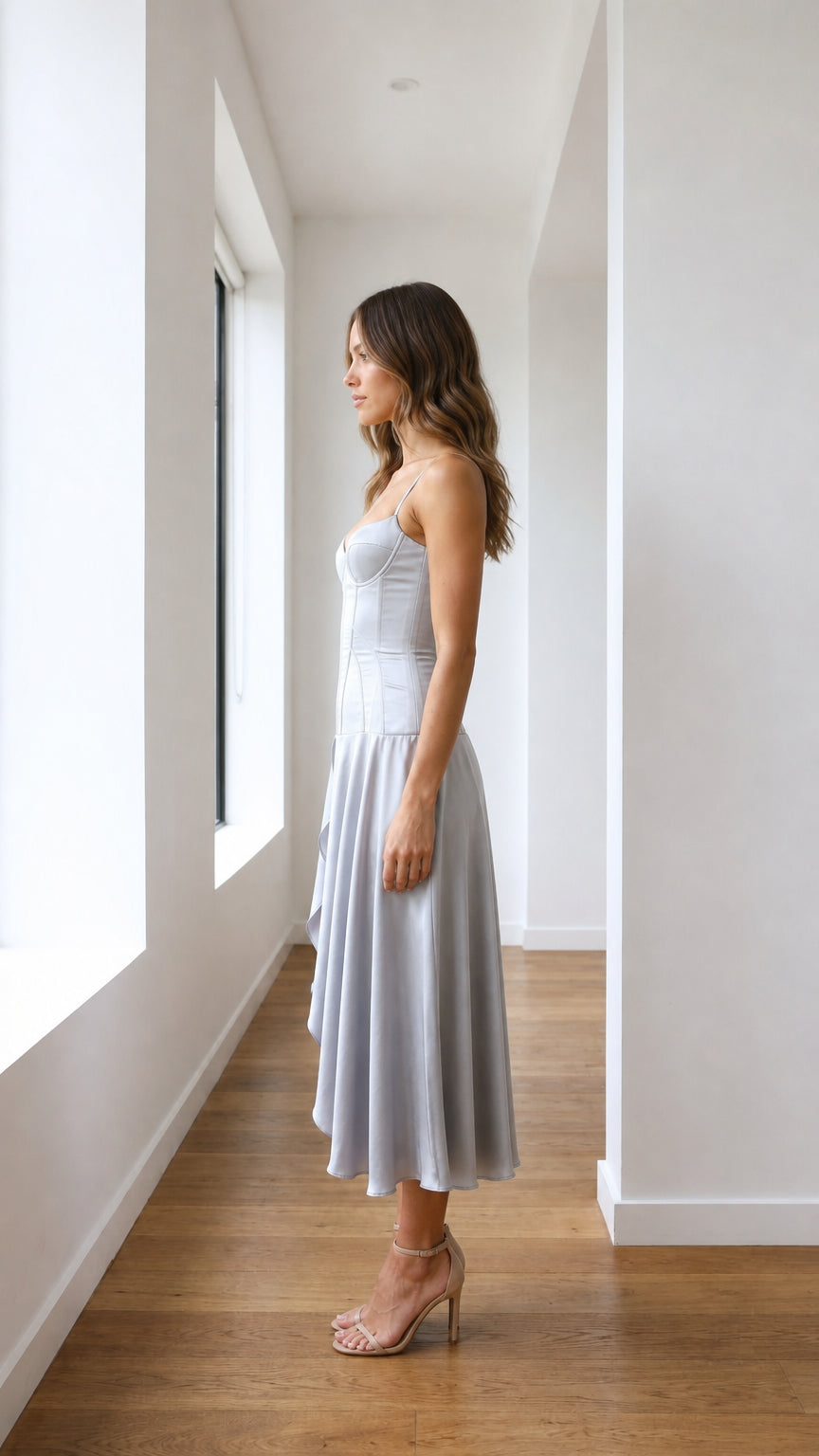 Silver satin-like corset midi dress shown from the side with flowing midi skirt