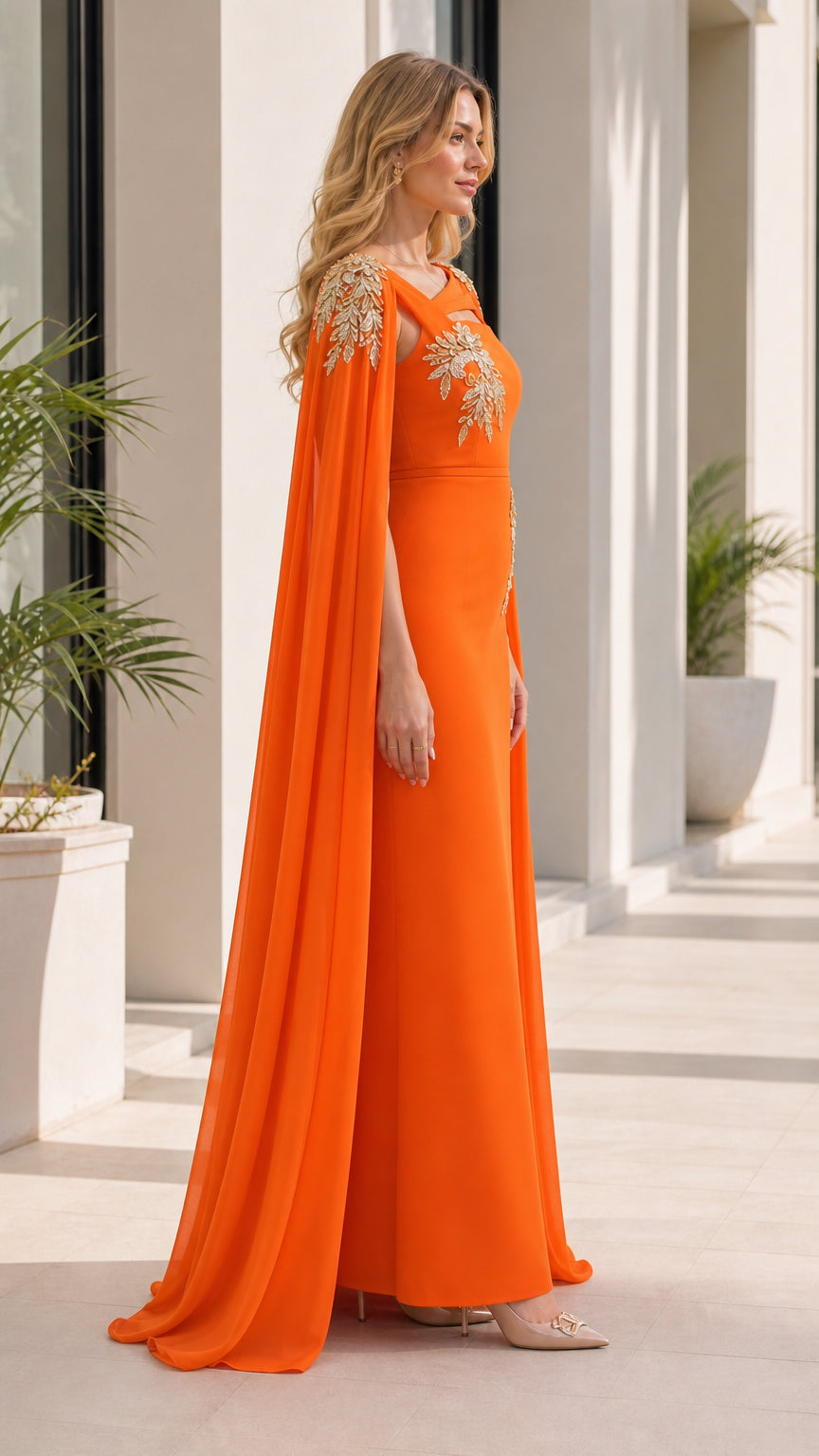 Side profile view of orange evening dress with flowing cape