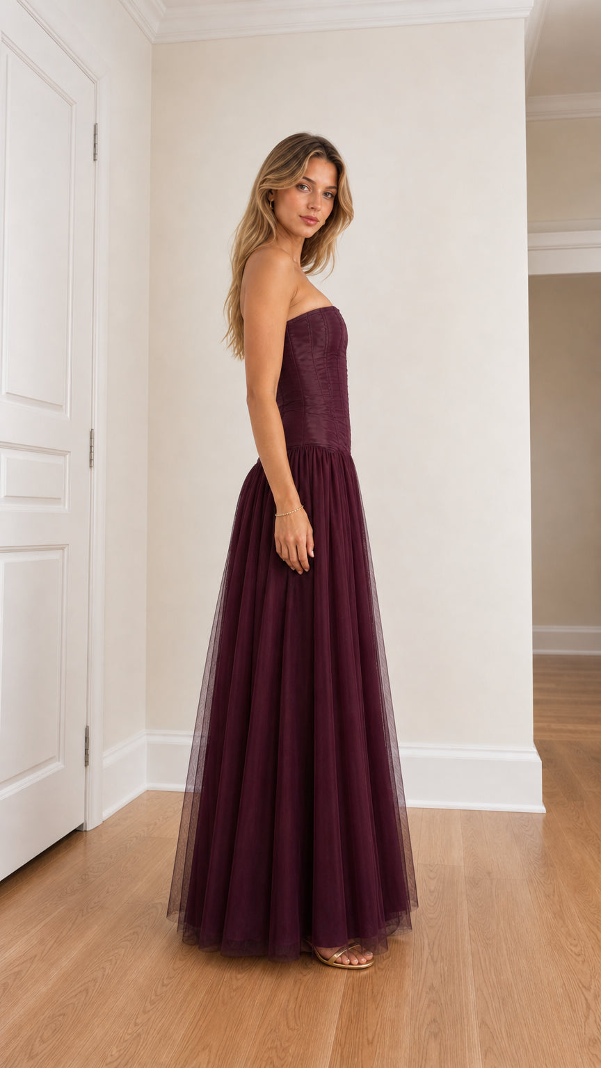 Side profile view of burgundy strapless corset tulle maxi dress