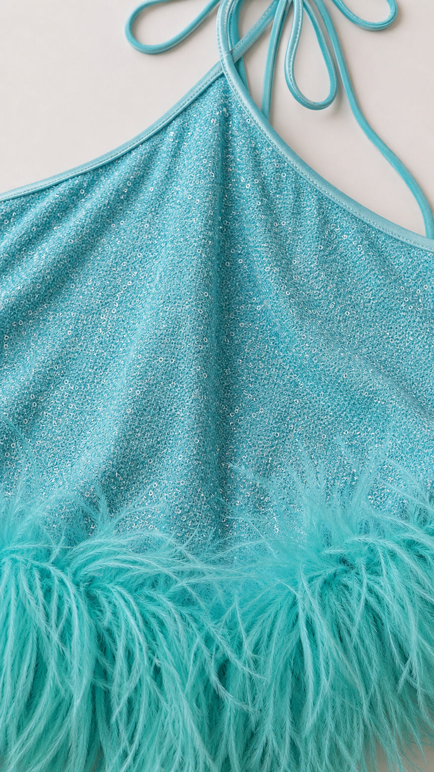 Close up of glitter fabric and turquoise feather hem