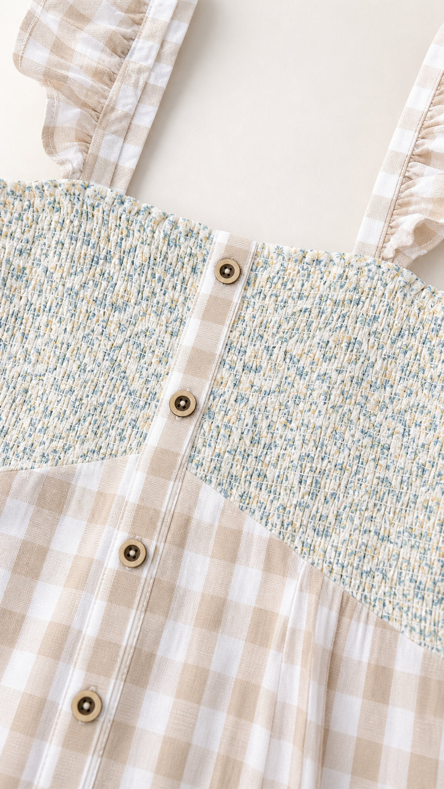 Close-up detail of smocked floral bodice and buttons on beige dress