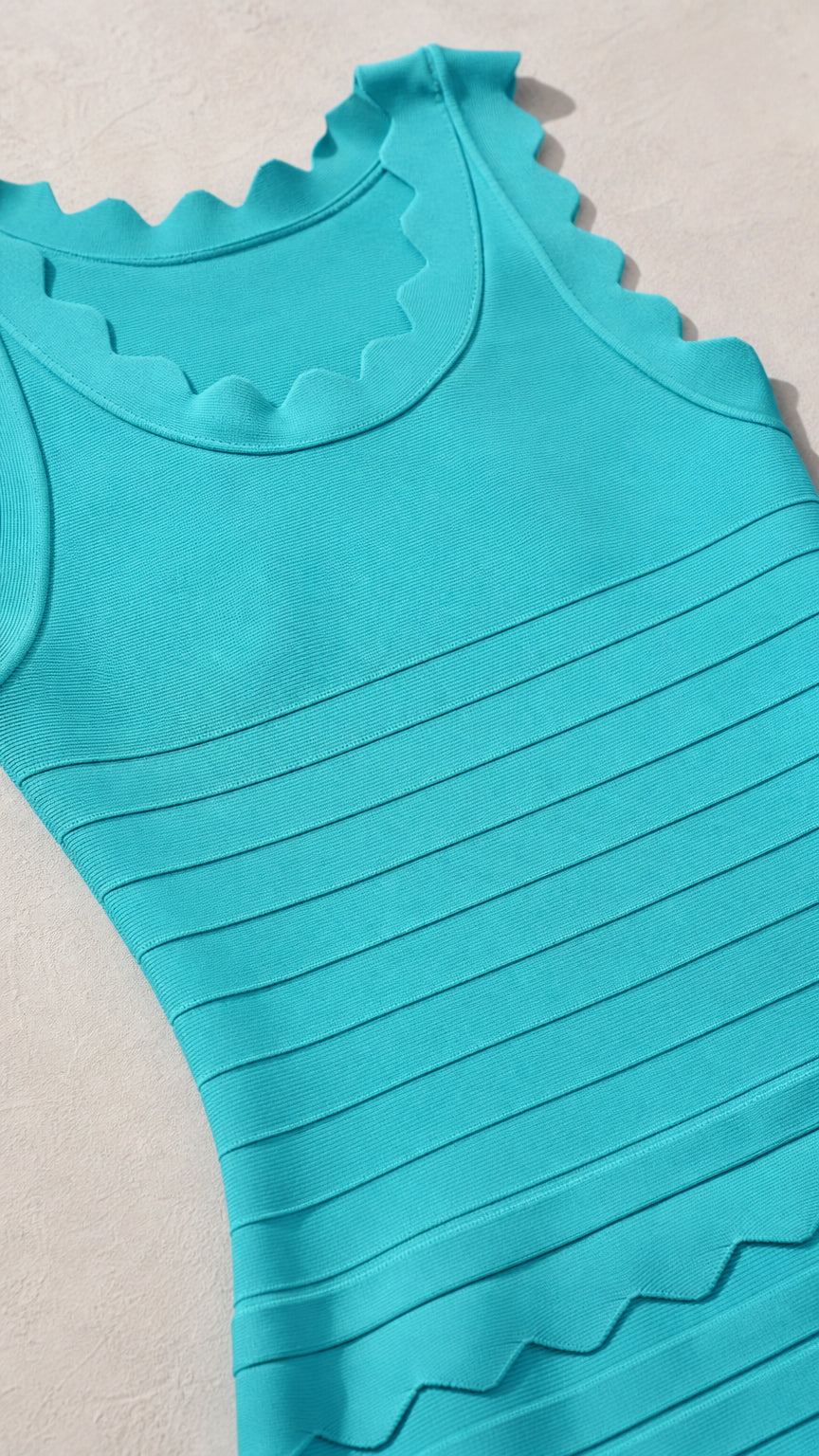 Close-up detail of turquoise ribbed knit fabric and scallop collar