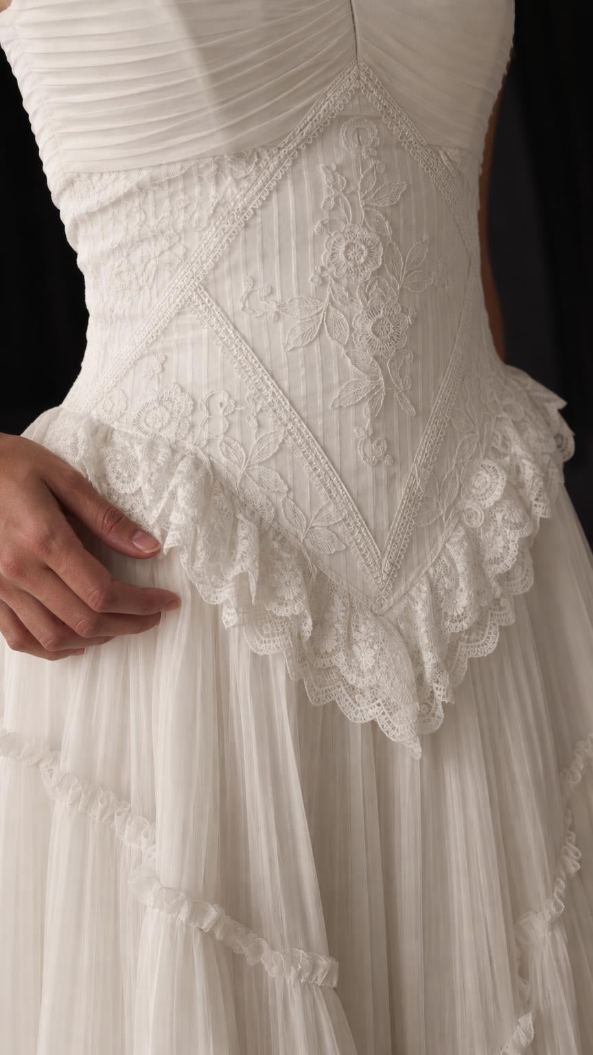Close-up detail of lace corset bodice and ruffled trim on white gown