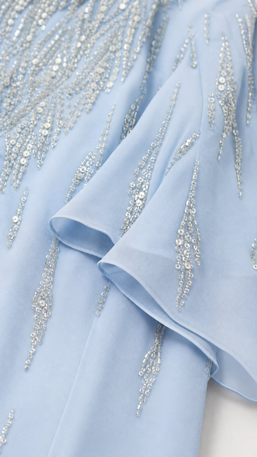 Close-up detail of light blue fabric beadwork and ruffles