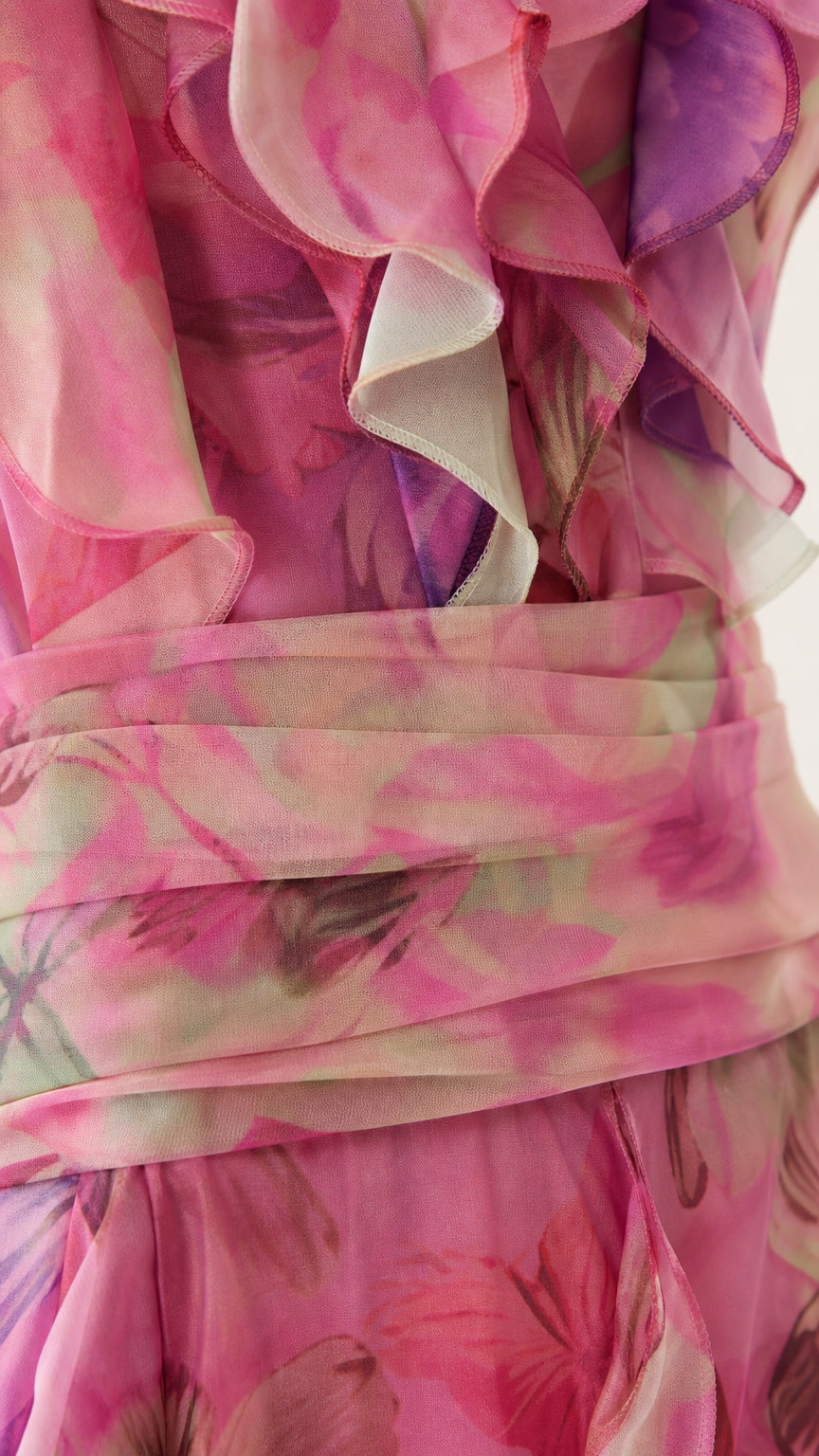 Close-up detail of ruffle trim and pleated waistband on pink floral dress
