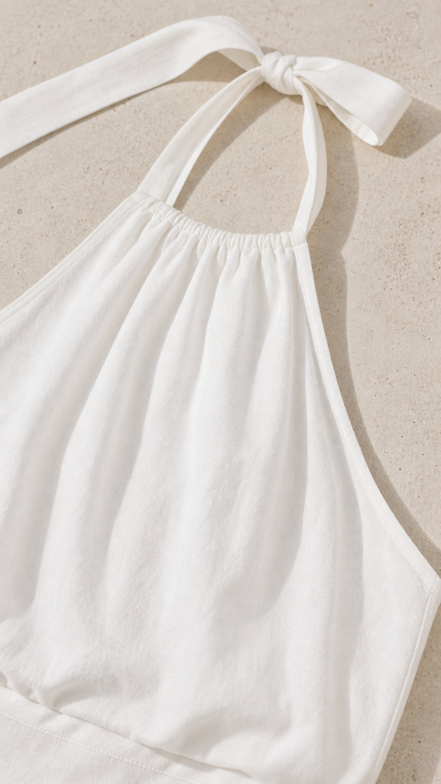 Close-up of the gathered halter neck and tie detail in white