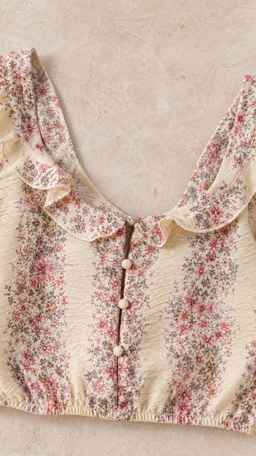 Close-up detail of beige floral crop top with ruffles and buttons
