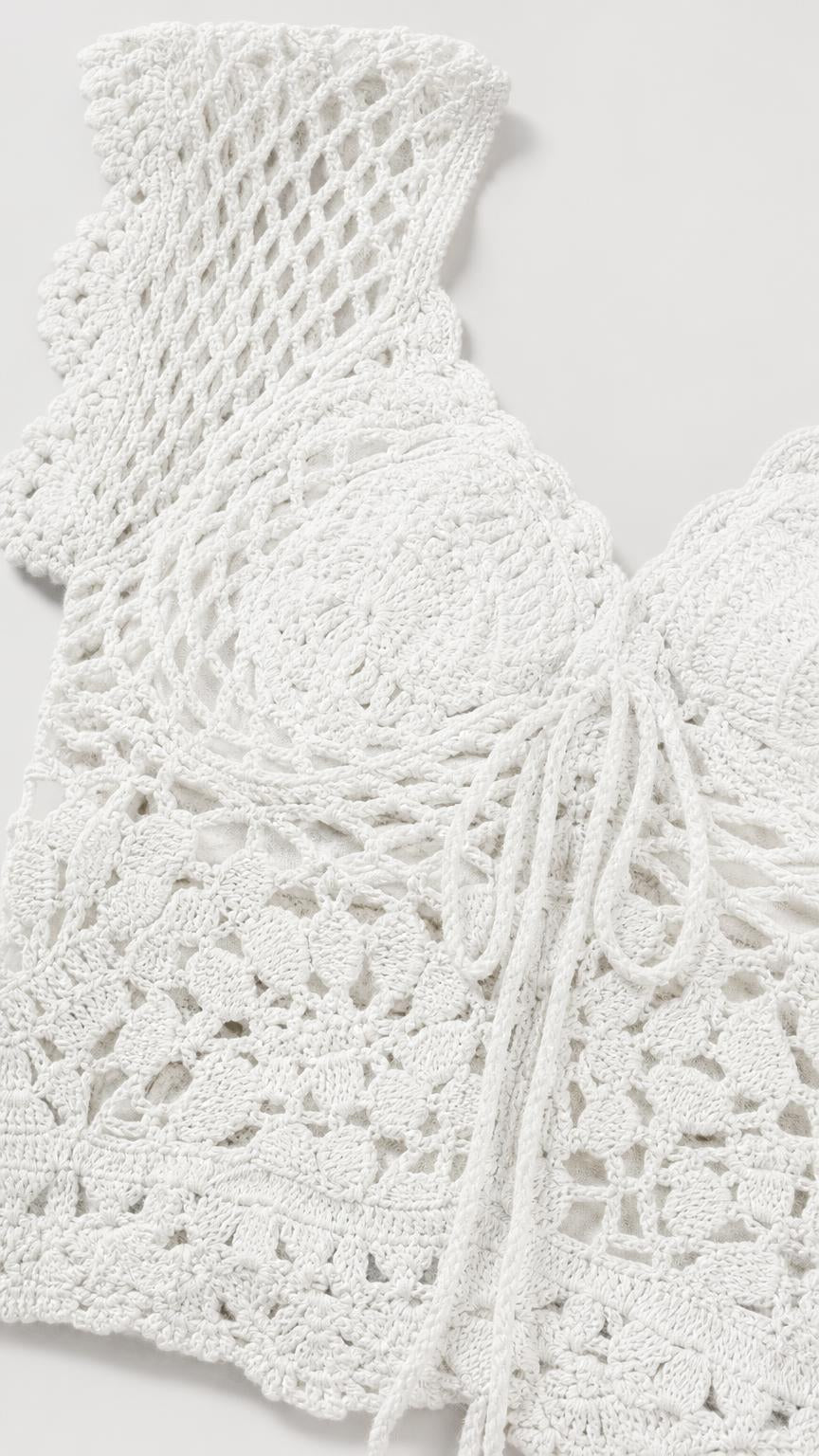 Close-up detail of white textured crochet knit top fabric