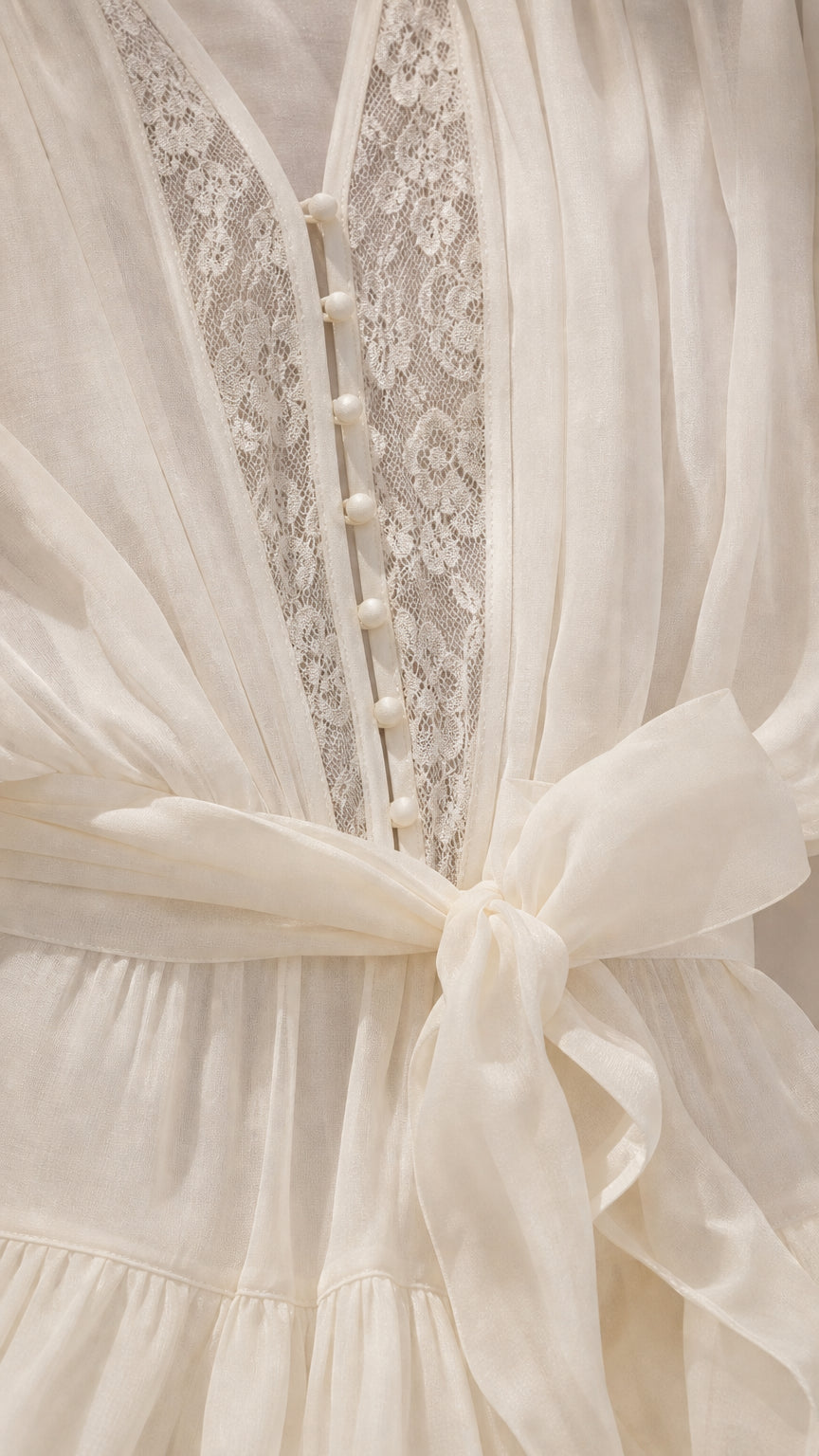 Close up of bodice buttons, lace, and tie belt on ivory romper