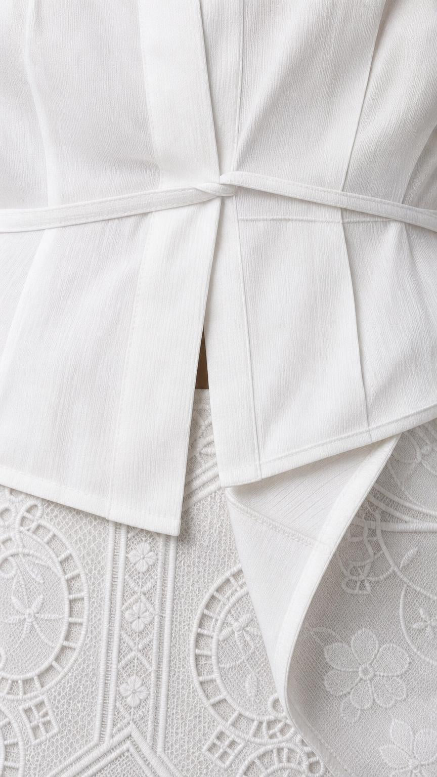 Close-up detail of white peplum top waist and textured skirt pattern