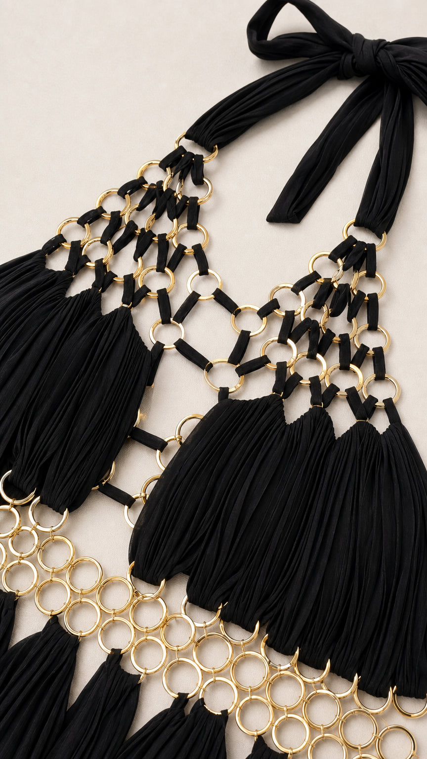 Close-up of gold chain hardware and pleated black fabric detail