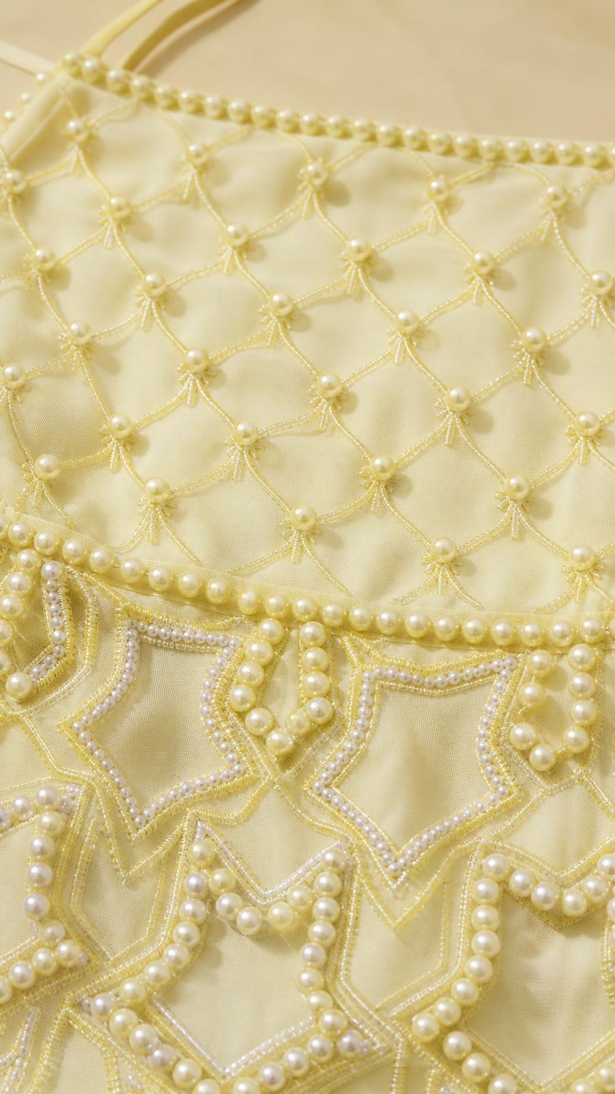 Close-up detail of geometric pearl beadwork on yellow dress