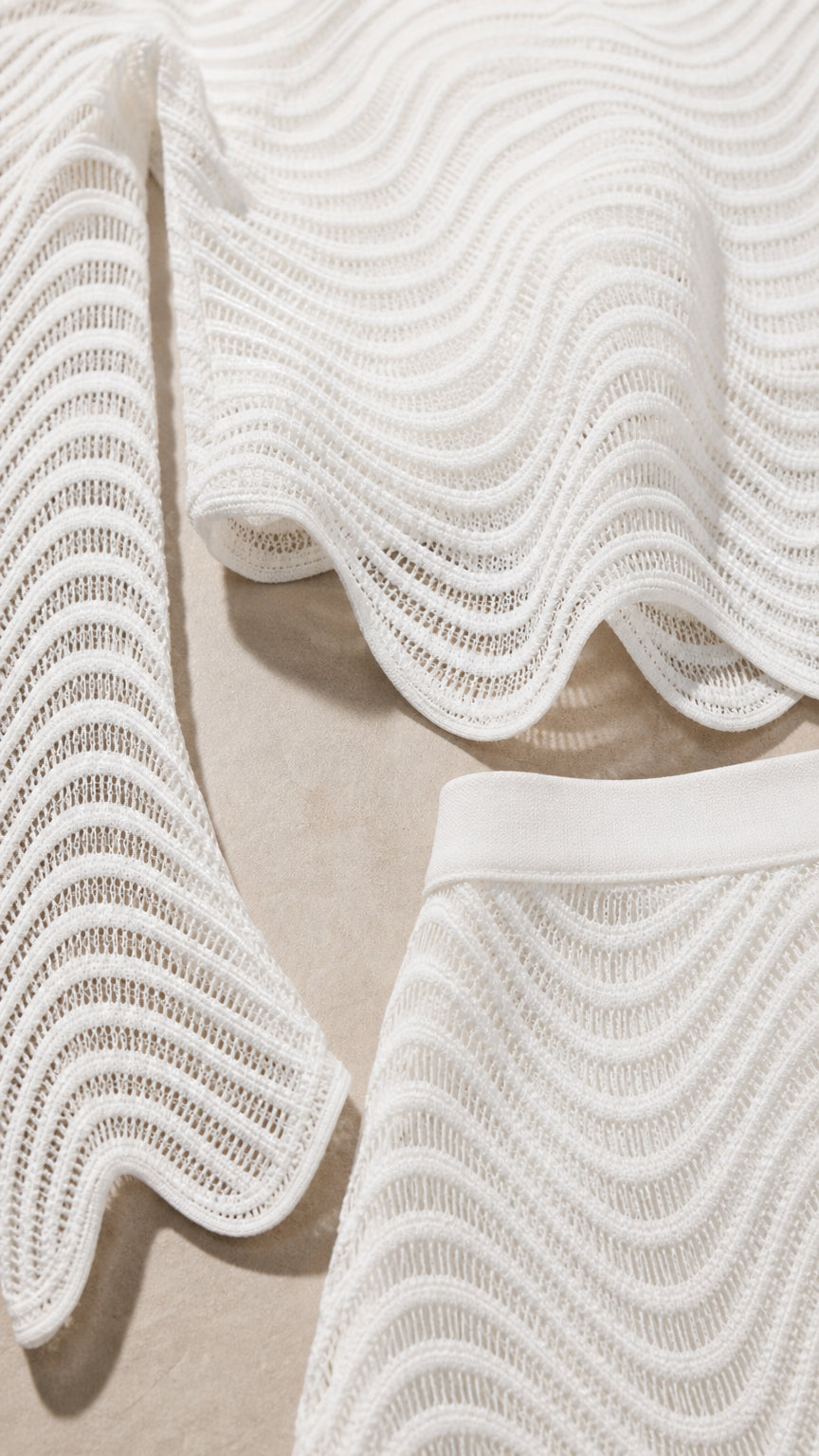 Close-up detail of white wavy knit fabric and curved hem