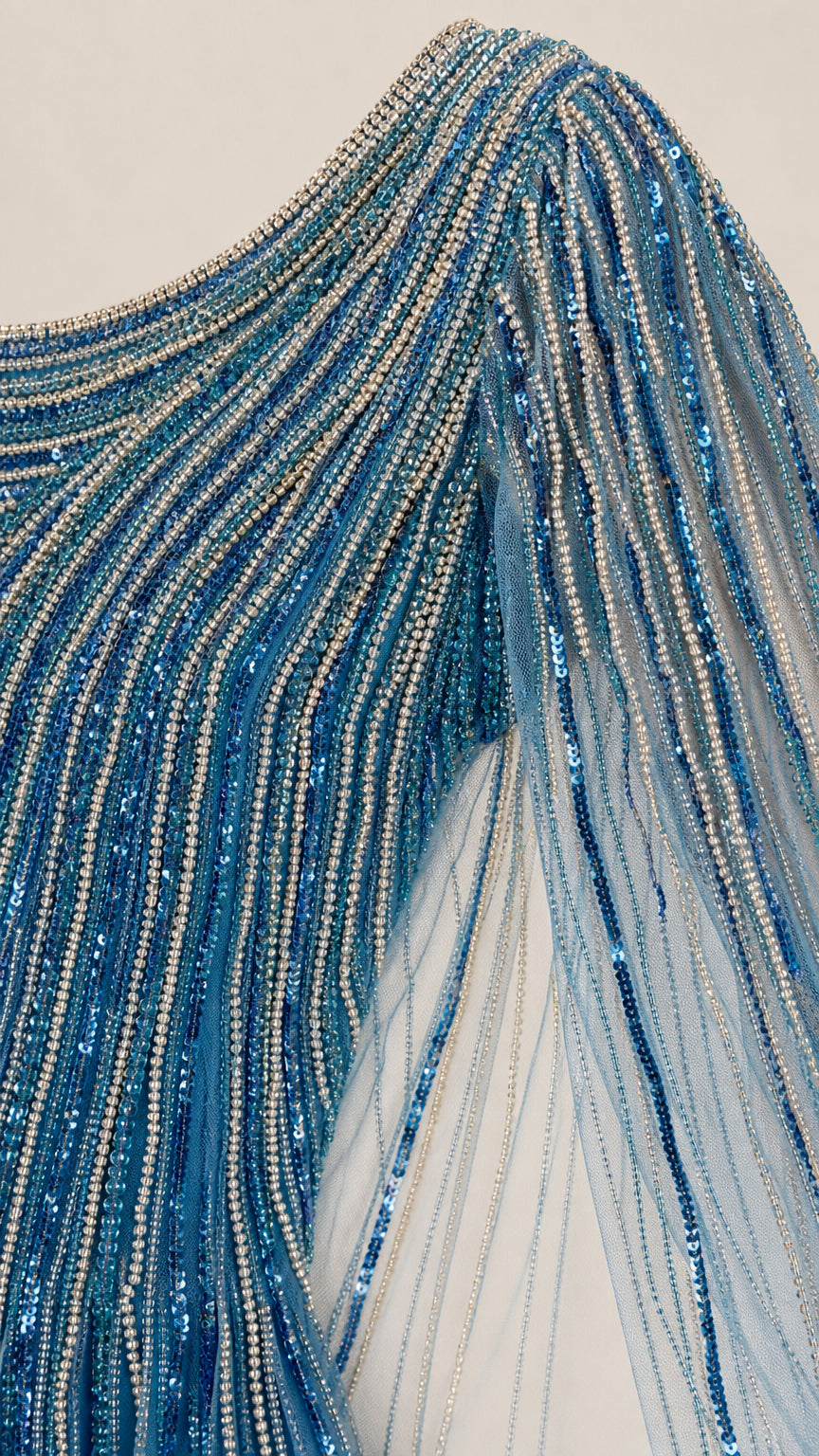 Close up detail of intricate linear beading and sequins on blue tulle fabric