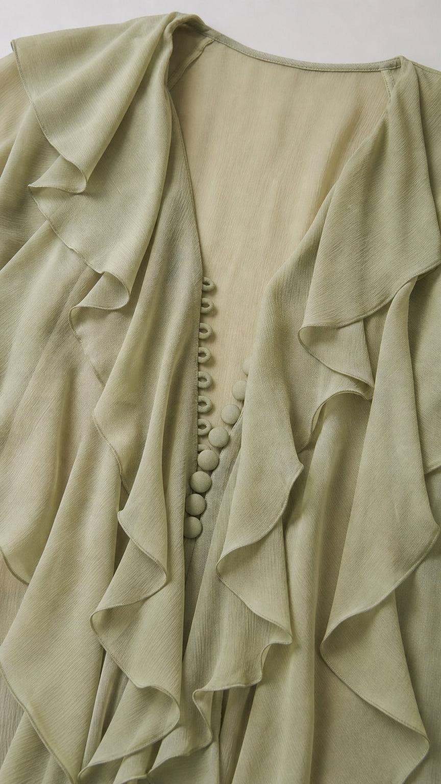 Close-up detail of ruffle collar and button front on sage green dress
