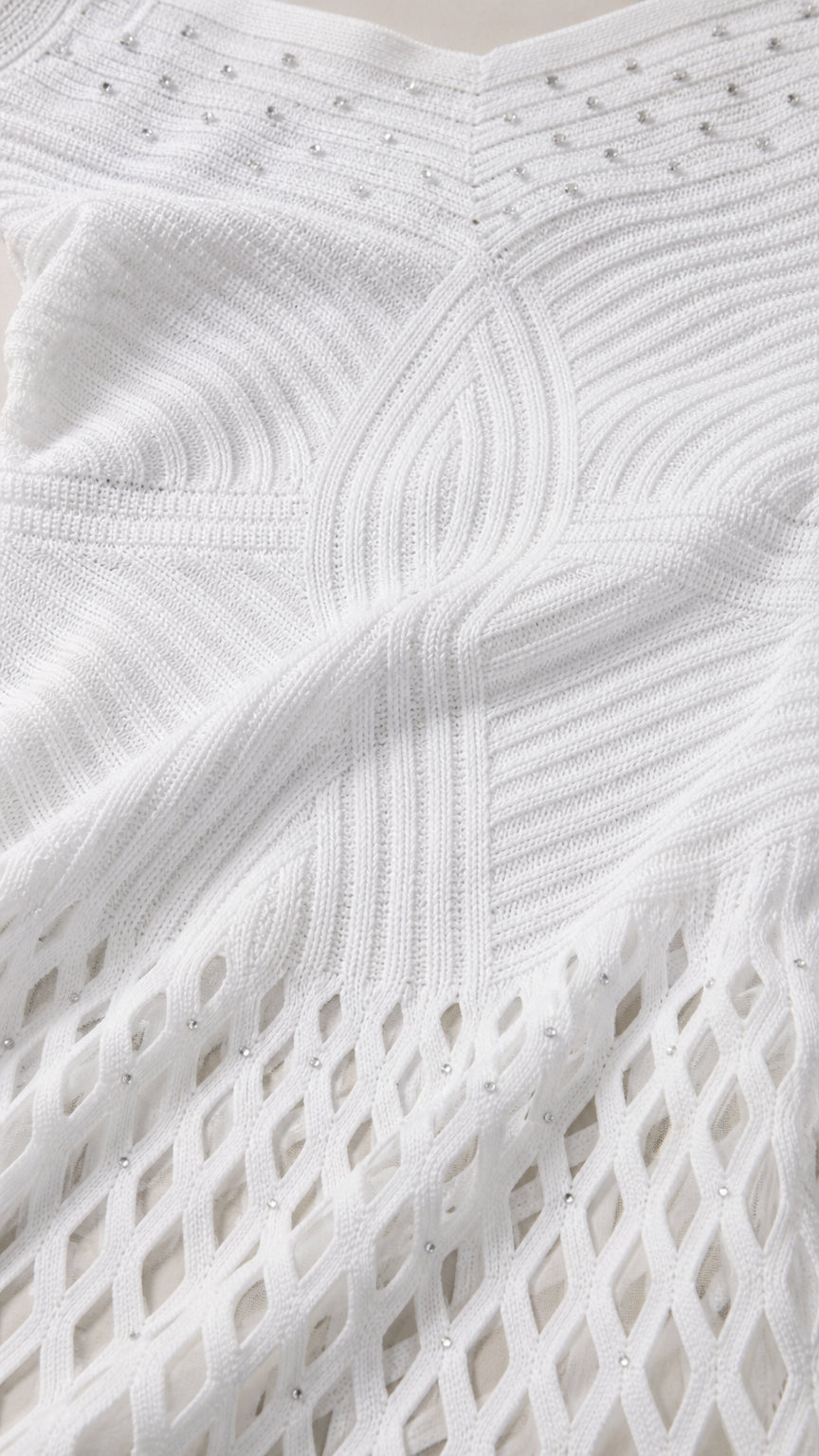 Close-up of white knit fabric texture and embellished bodice details